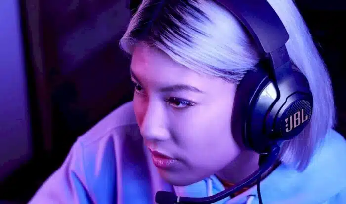Une femme &eacute;quip&eacute;e d'un casque gamer pour PS4 et PS5 joue &agrave; un jeu vid&eacute;o