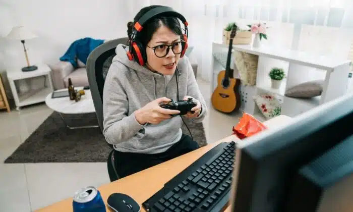Une femme &eacute;quip&eacute; d'un casque gamer pour PS4 et PS5 joue &agrave; un jeu vid&eacute;o