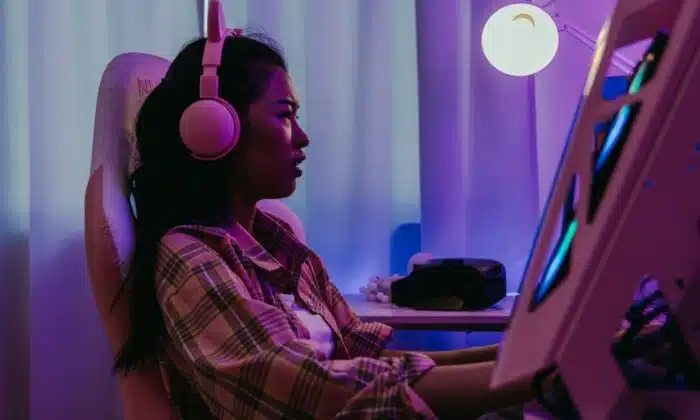 Une femme &eacute;quip&eacute;e d'un casque gamer pour PS4 et PS5 joue &agrave; un jeu vid&eacute;o