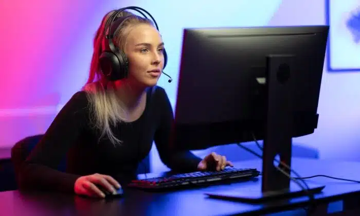 Une femme &eacute;quip&eacute;e d'un casque gamer pour PS4 et PS5 joue &agrave; un jeu vid&eacute;o